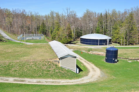 The Authority's treatment plant from above: the filter building, a round tank and a blue storage tank in the woods
